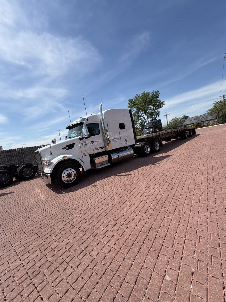 A CARVI Logistics tractor coupled to a flatbed trailer, parked on brick paving.