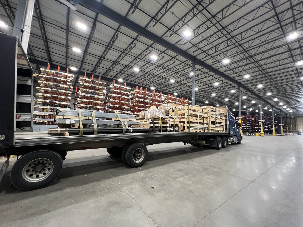 A flatbed trailer loaded with freight inside a warehouse.