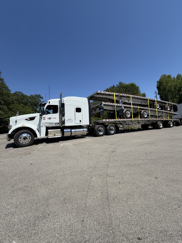 A CARVI tractor hauling an open-deck load under clear skies.
